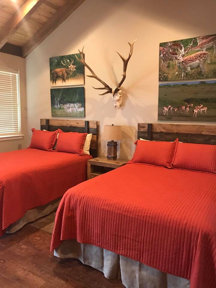 Rustic hunting cabin bedroom with vaulted cedar beam ceiling inside a barndominium by Tincher's Custom Homes