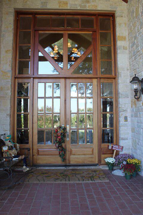 Grand wood French double door entry with full-height transom windows in limestone home exterior — Tincher's Custom Homes